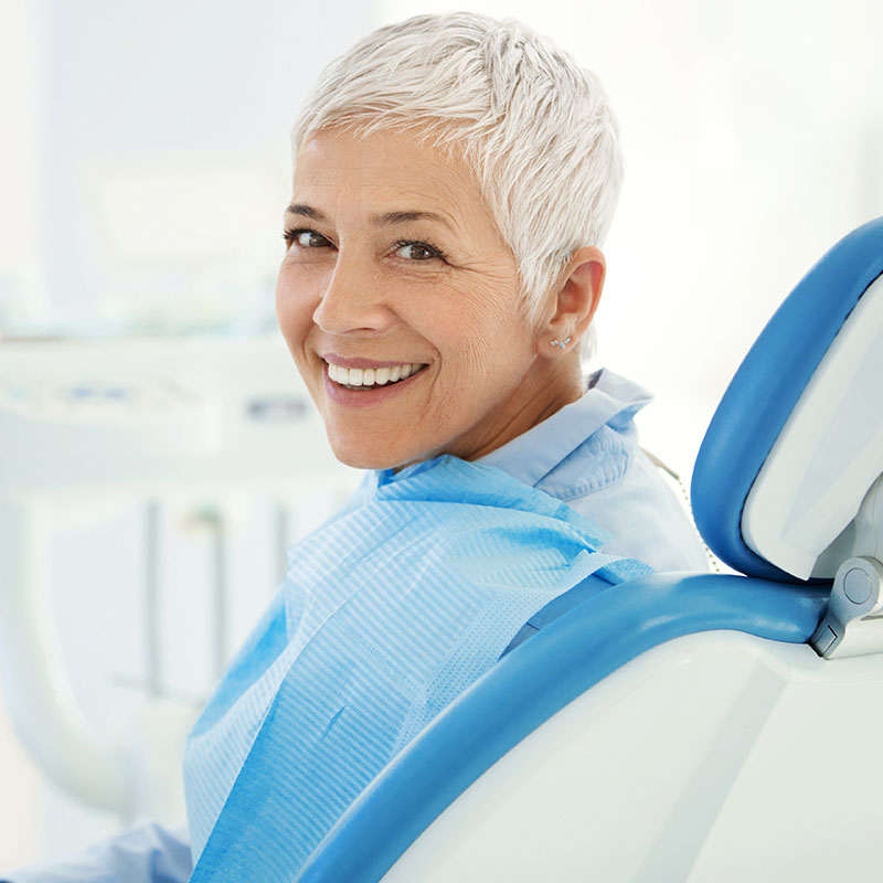 Cheerful mid 50's female patient happily smiling after dental procedure.